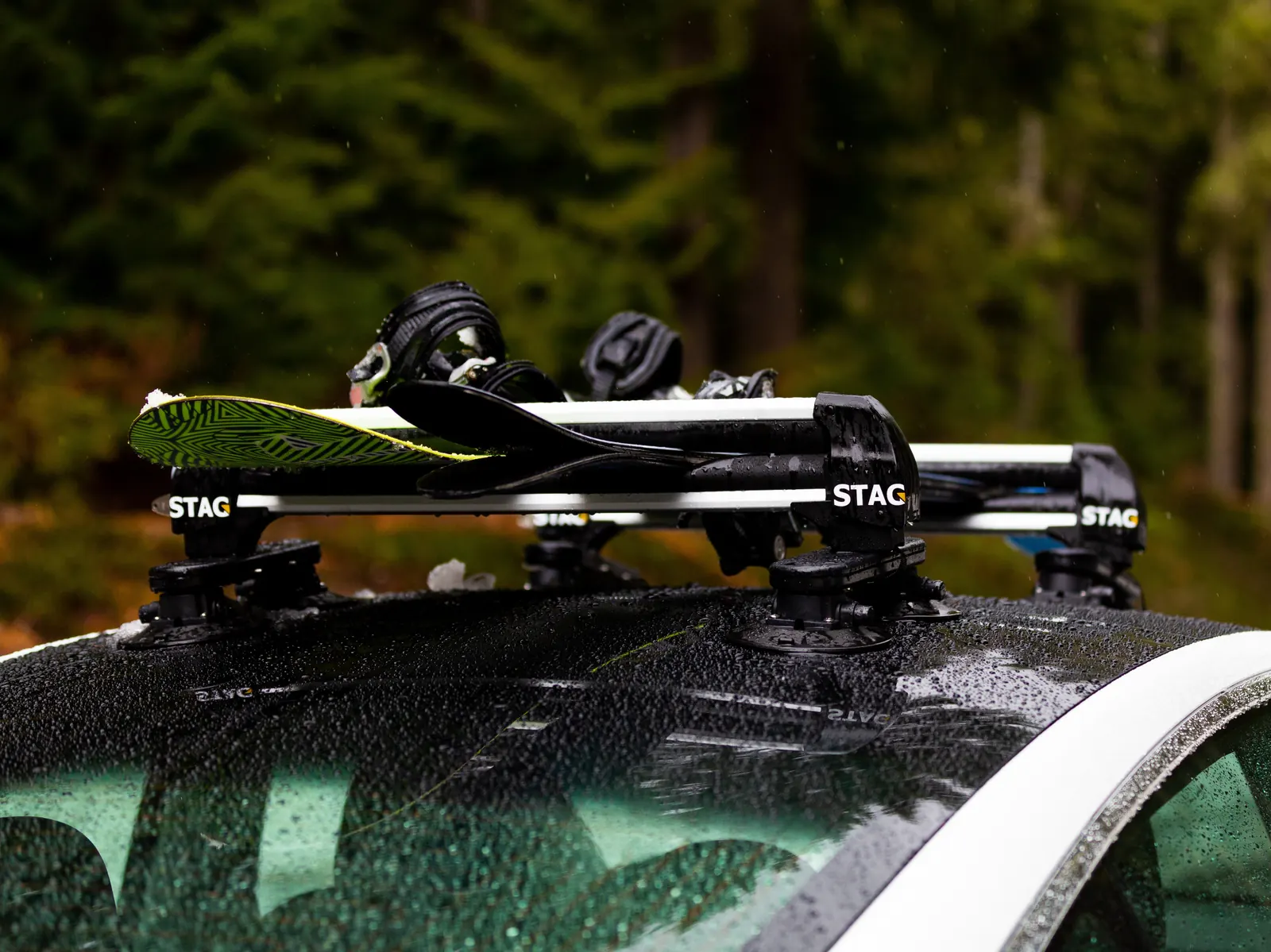 STAG ski rack with a snowboard on a wet car roof